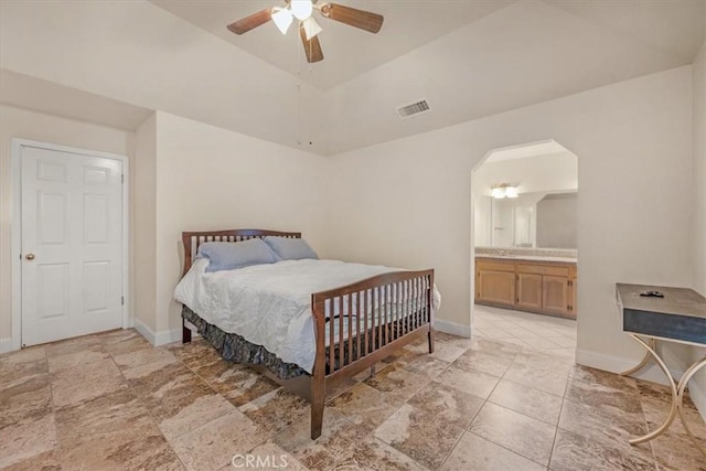 bedroom with vaulted ceiling, connected bathroom, ceiling fan, and a tray ceiling