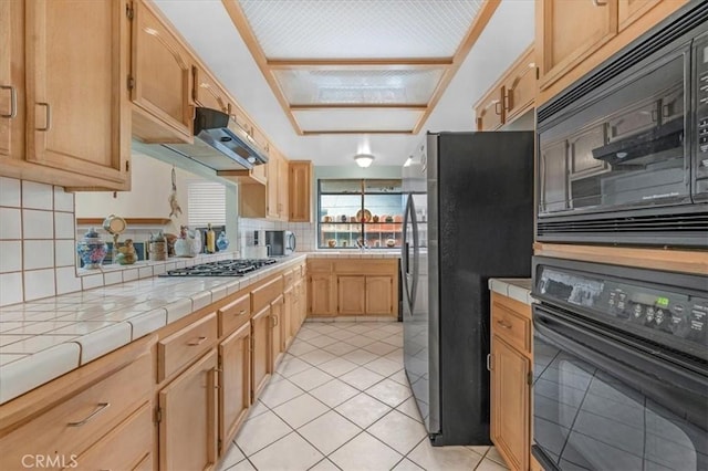 kitchen with backsplash, tile counters, light tile patterned floors, and black appliances