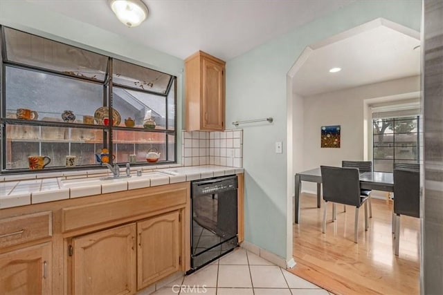 kitchen featuring light tile patterned flooring, tile countertops, dishwasher, and backsplash