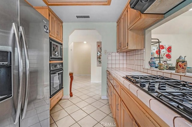 kitchen with light tile patterned flooring, tile countertops, stainless steel appliances, decorative backsplash, and exhaust hood