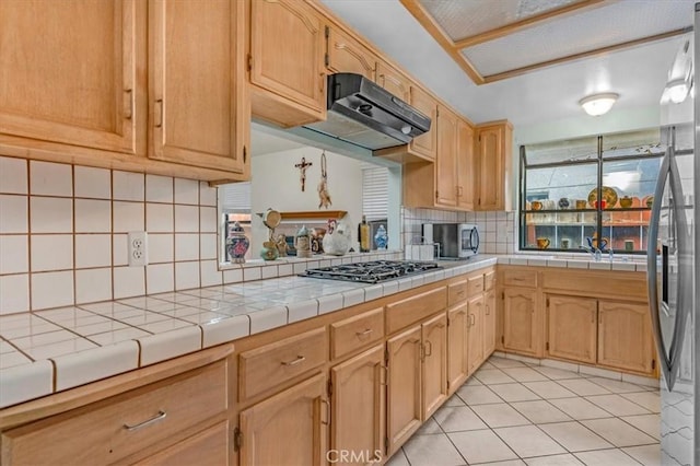 kitchen featuring tasteful backsplash, tile counters, stainless steel appliances, and light tile patterned flooring