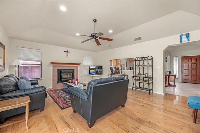 living room featuring lofted ceiling, light hardwood / wood-style floors, and a tile fireplace