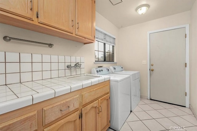 laundry room with sink, light tile patterned floors, cabinets, and washing machine and clothes dryer