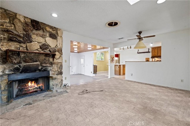 unfurnished living room featuring ceiling fan, light colored carpet, a fireplace, and a textured ceiling