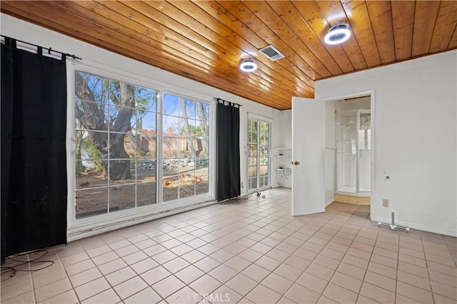 spare room featuring wood ceiling, a barn door, and light tile patterned flooring