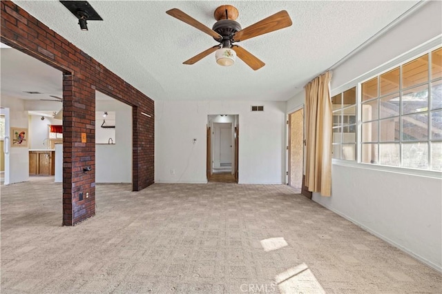 unfurnished room with ceiling fan, light carpet, and a textured ceiling