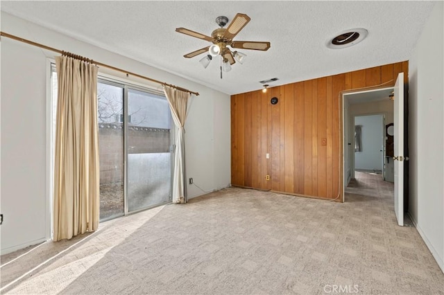 unfurnished bedroom with a textured ceiling, light carpet, access to exterior, and wooden walls