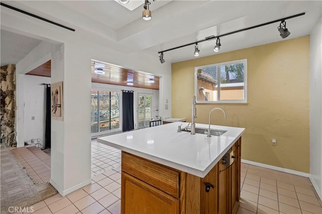 kitchen featuring sink, a center island with sink, track lighting, and light tile patterned floors