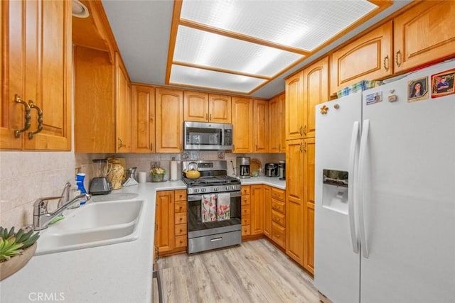 kitchen with sink, decorative backsplash, light wood-type flooring, and appliances with stainless steel finishes