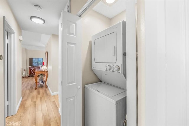 clothes washing area featuring stacked washer / dryer and light wood-type flooring