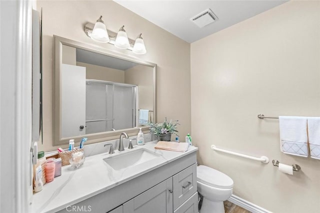 bathroom with vanity, a shower with shower door, and toilet