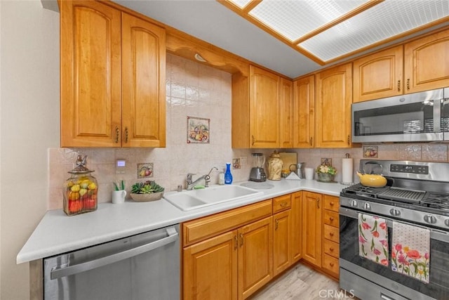 kitchen featuring appliances with stainless steel finishes, sink, backsplash, and light wood-type flooring