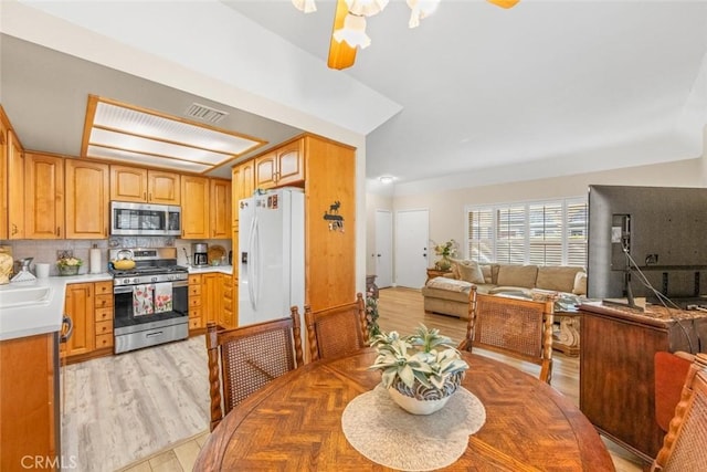 dining room with ceiling fan, sink, and light wood-type flooring