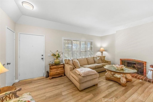 living room featuring a brick fireplace and light hardwood / wood-style flooring