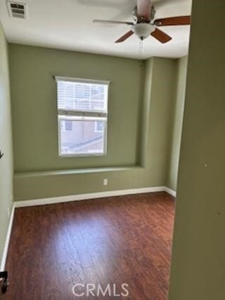 unfurnished room with baseboards, visible vents, ceiling fan, and dark wood-type flooring