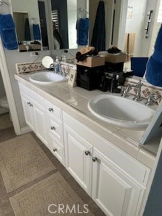 full bath with double vanity, a sink, and tile patterned floors