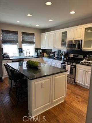 kitchen featuring white cabinets, glass insert cabinets, stainless steel appliances, and a center island