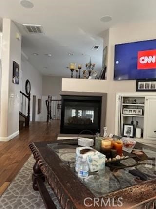 living room featuring wood finished floors, a glass covered fireplace, and visible vents