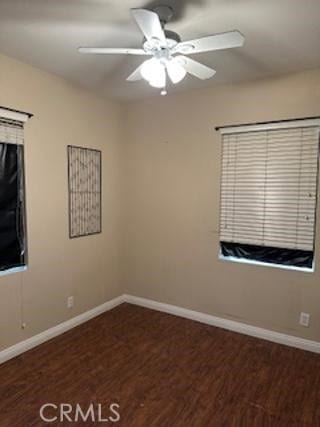 spare room featuring ceiling fan, baseboards, and dark wood-type flooring