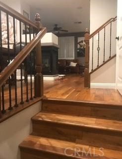 stairway featuring ceiling fan, a fireplace, and wood finished floors