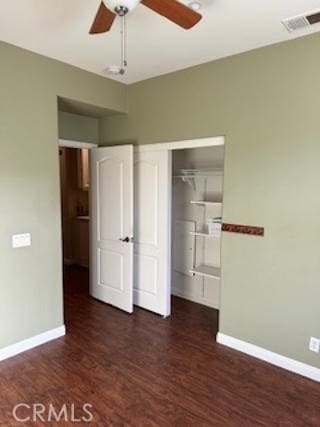 unfurnished bedroom with dark wood-style flooring, visible vents, and baseboards