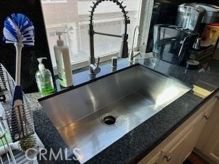 interior details featuring dark stone counters, a sink, and light brown cabinetry