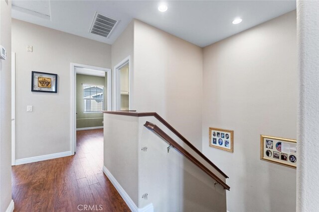 hallway featuring visible vents, wood finished floors, baseboards, an upstairs landing, and recessed lighting