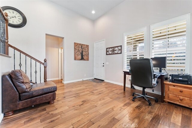office space with baseboards, a high ceiling, wood finished floors, and recessed lighting