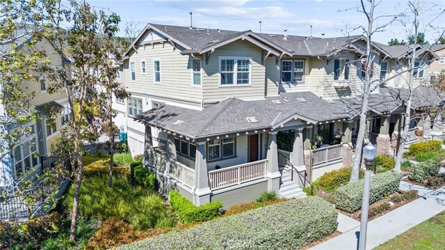 multi unit property featuring a shingled roof and a porch