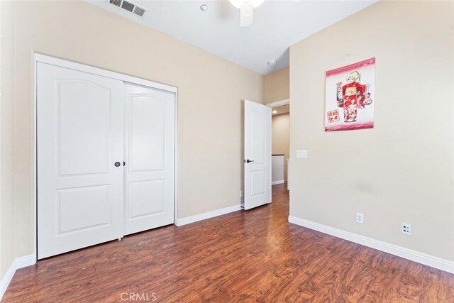unfurnished bedroom featuring baseboards, a closet, wood finished floors, and visible vents