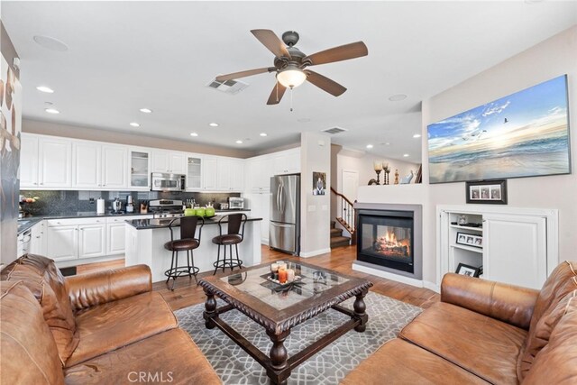 22 Arlington St, Ladera Ranch, CA 92694 - living area featuring light wood-style flooring, a ceiling fan, recessed lighting, a glass covered fireplace, and baseboards