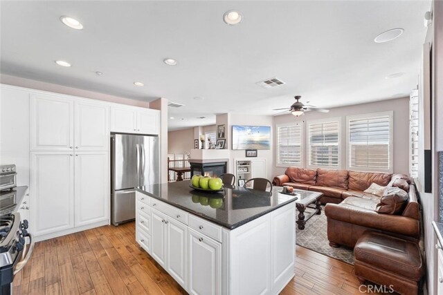 kitchen featuring white cabinets, appliances with stainless steel finishes, light wood finished floors, open floor plan, and visible vents