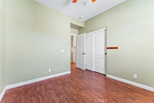 unfurnished bedroom featuring baseboards, ceiling fan, wood finished floors, and a closet
