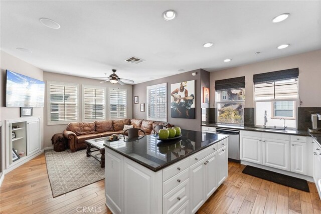 kitchen with light wood-style floors, white cabinetry, dishwasher, and visible vents