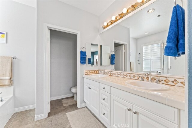 full bath with a sink, a garden tub, toilet, and double vanity