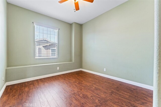 empty room with vaulted ceiling, baseboards, a ceiling fan, and dark wood-style flooring