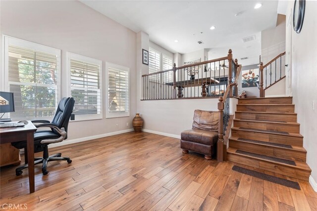 office space with baseboards, a healthy amount of sunlight, and hardwood / wood-style floors