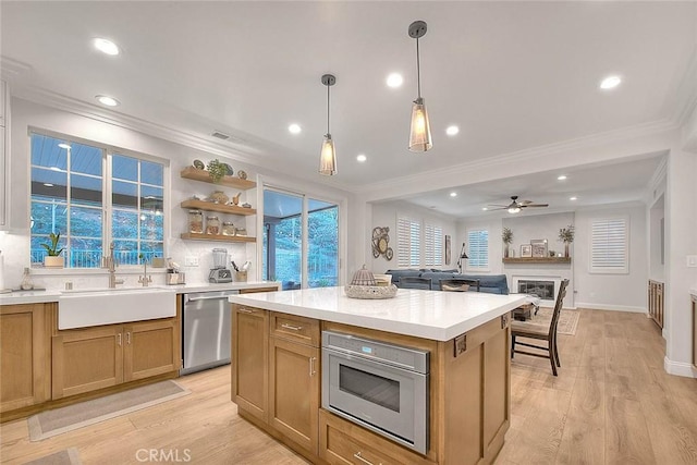 kitchen featuring sink, appliances with stainless steel finishes, light hardwood / wood-style floors, a kitchen island, and decorative light fixtures