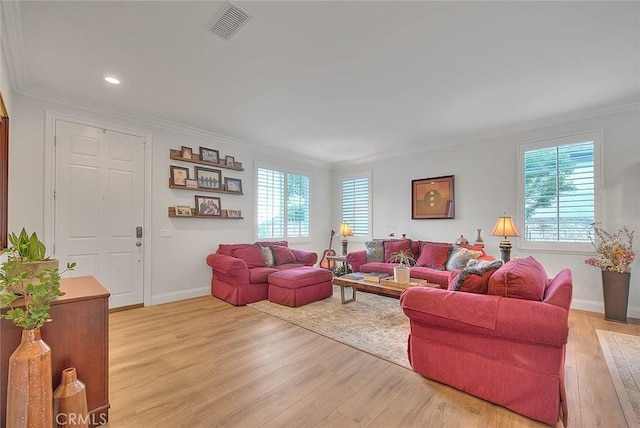 living room featuring ornamental molding, a wealth of natural light, and light wood-type flooring