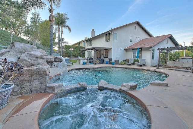 view of swimming pool with an in ground hot tub, pool water feature, a pergola, and a patio