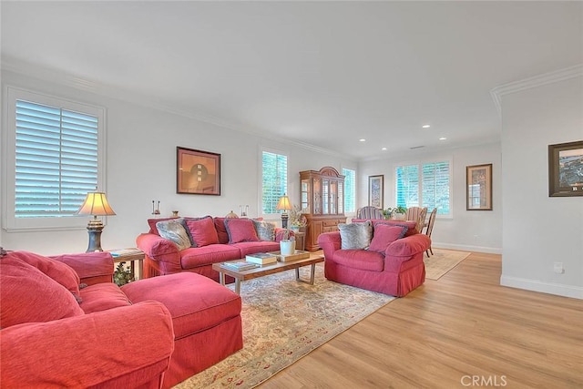 living room with crown molding, plenty of natural light, and light hardwood / wood-style flooring