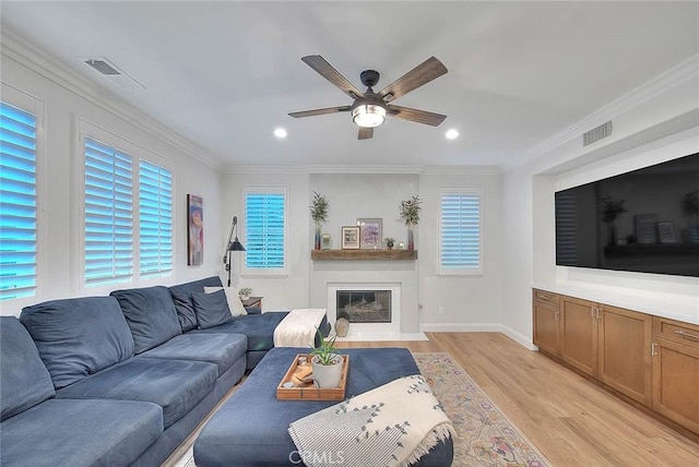 living room featuring ornamental molding, a large fireplace, ceiling fan, and light wood-type flooring