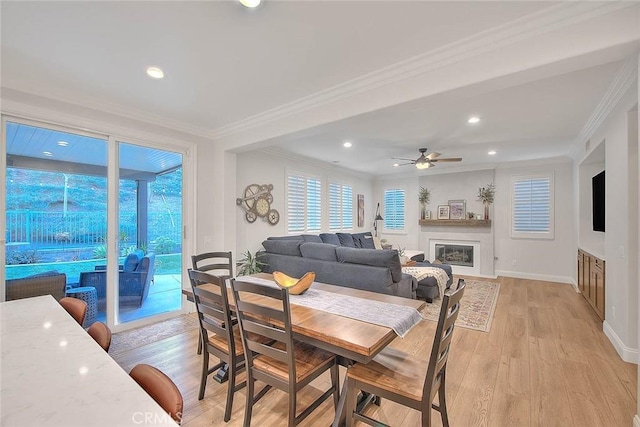 dining space with a healthy amount of sunlight, ornamental molding, and light wood-type flooring