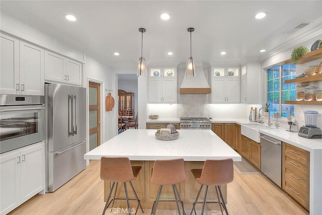 kitchen with sink, white cabinetry, stainless steel appliances, a center island, and decorative light fixtures