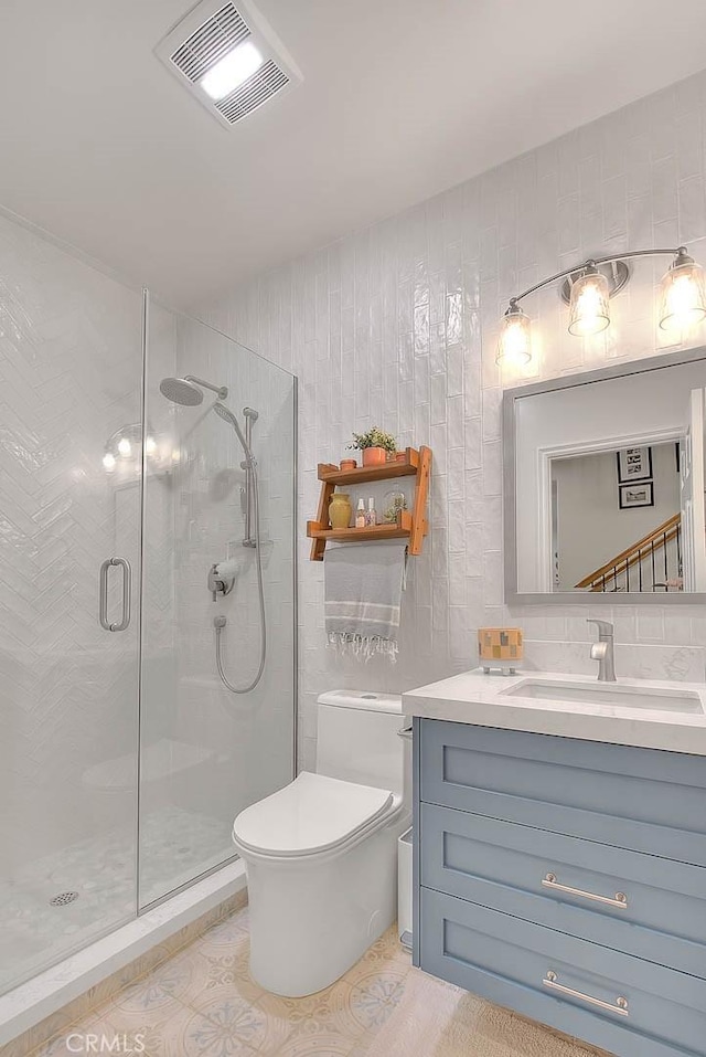 bathroom featuring an enclosed shower, vanity, decorative backsplash, and toilet