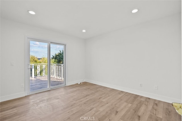 spare room featuring light wood-type flooring, baseboards, and recessed lighting