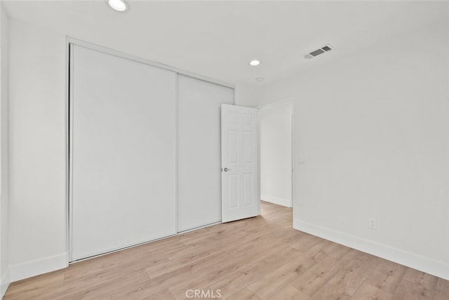 unfurnished bedroom with recessed lighting, a closet, visible vents, light wood-type flooring, and baseboards