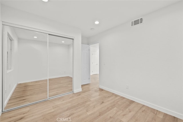 unfurnished bedroom with light wood-style flooring, recessed lighting, visible vents, baseboards, and a closet