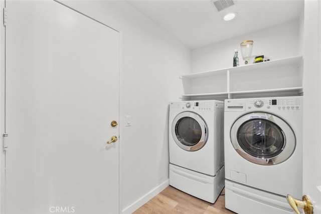 washroom with light hardwood / wood-style flooring and washing machine and dryer