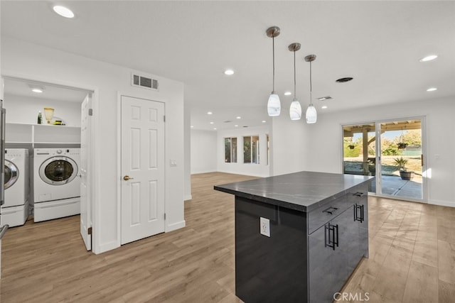 kitchen with washer and dryer, a center island, light hardwood / wood-style floors, and decorative light fixtures